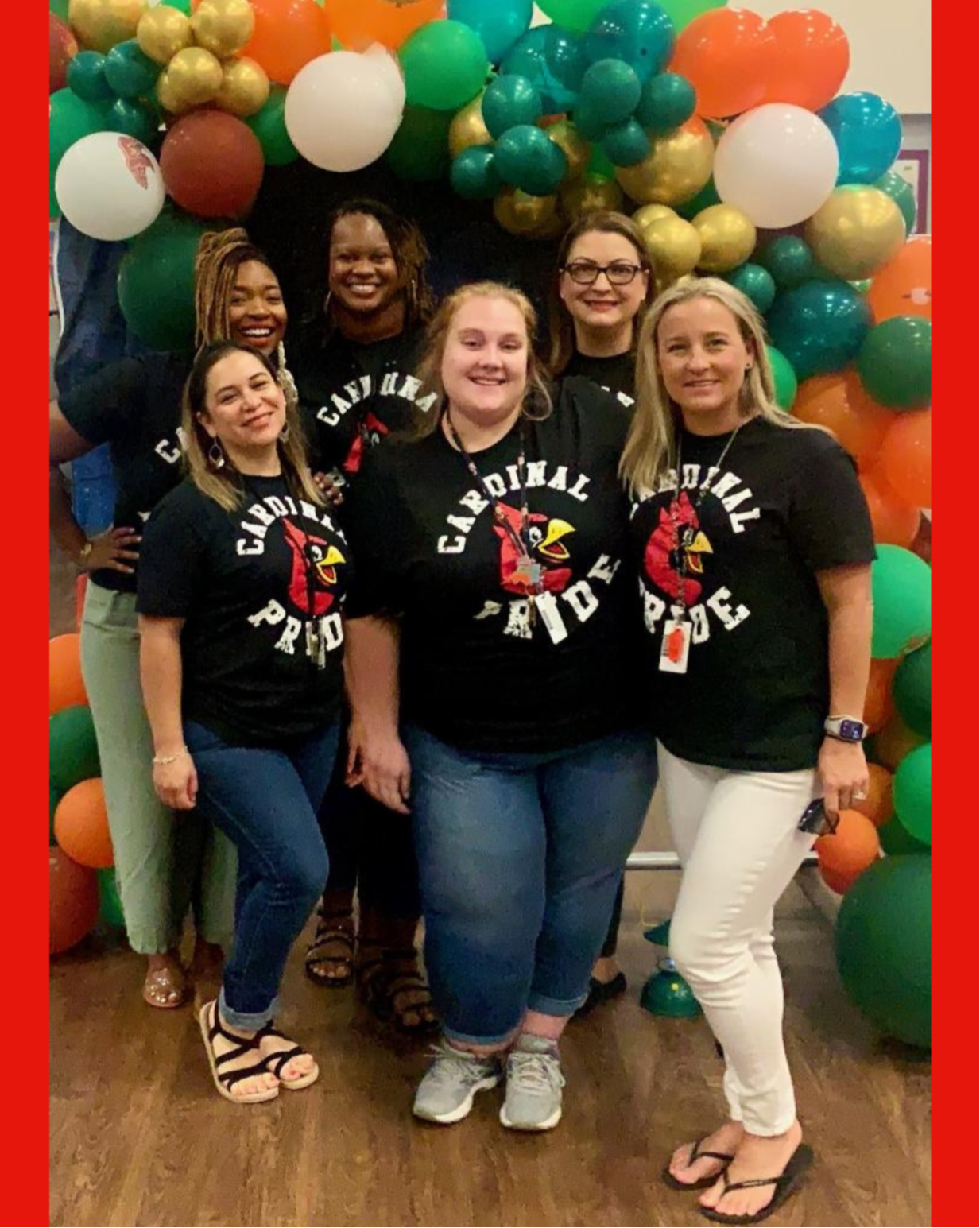 teachers in black shirts with cardinals posing with balloons