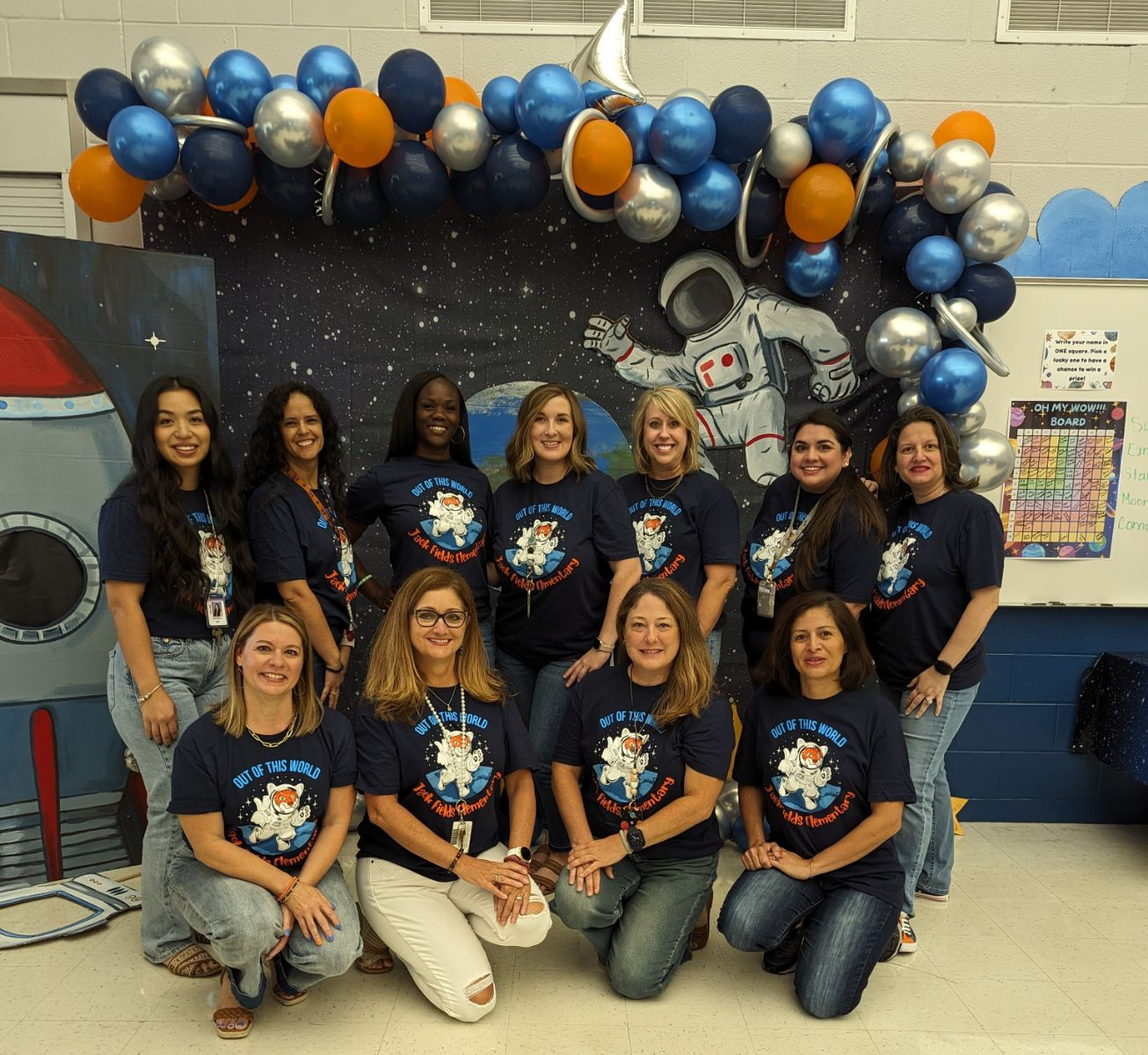 group of ladies posing in blue shirts under balloons