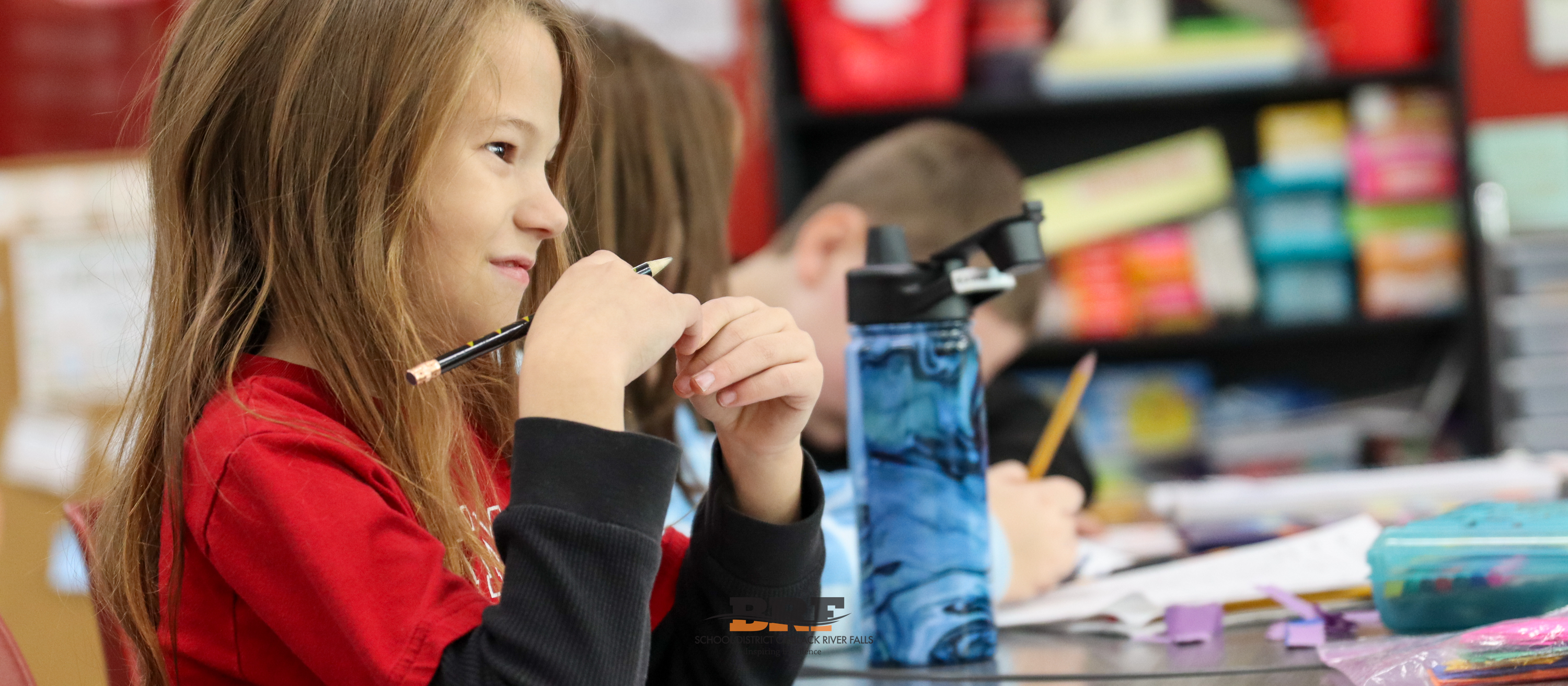 Student smiles while sitting at a table.