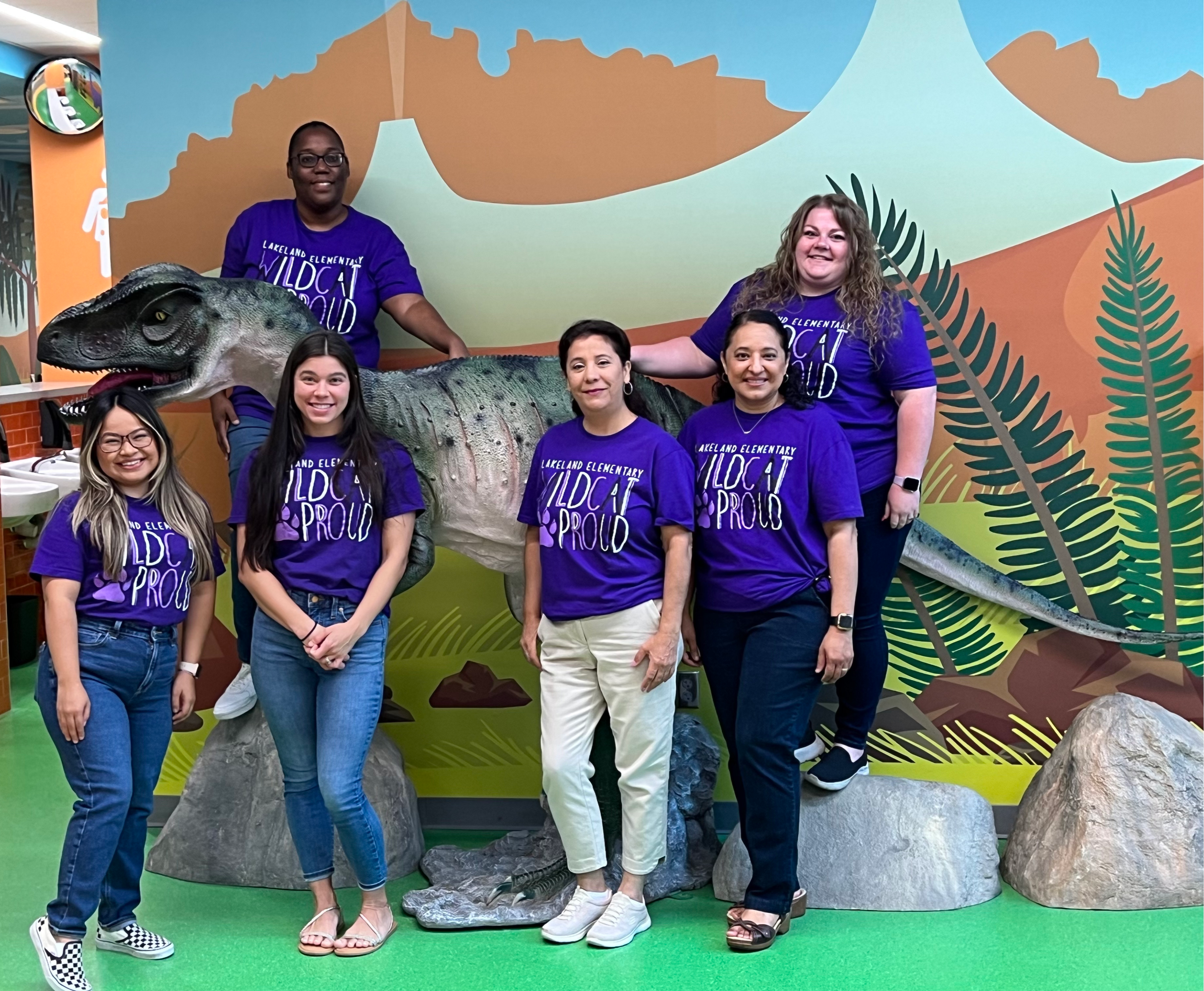 group of people posing with dinosaur statue