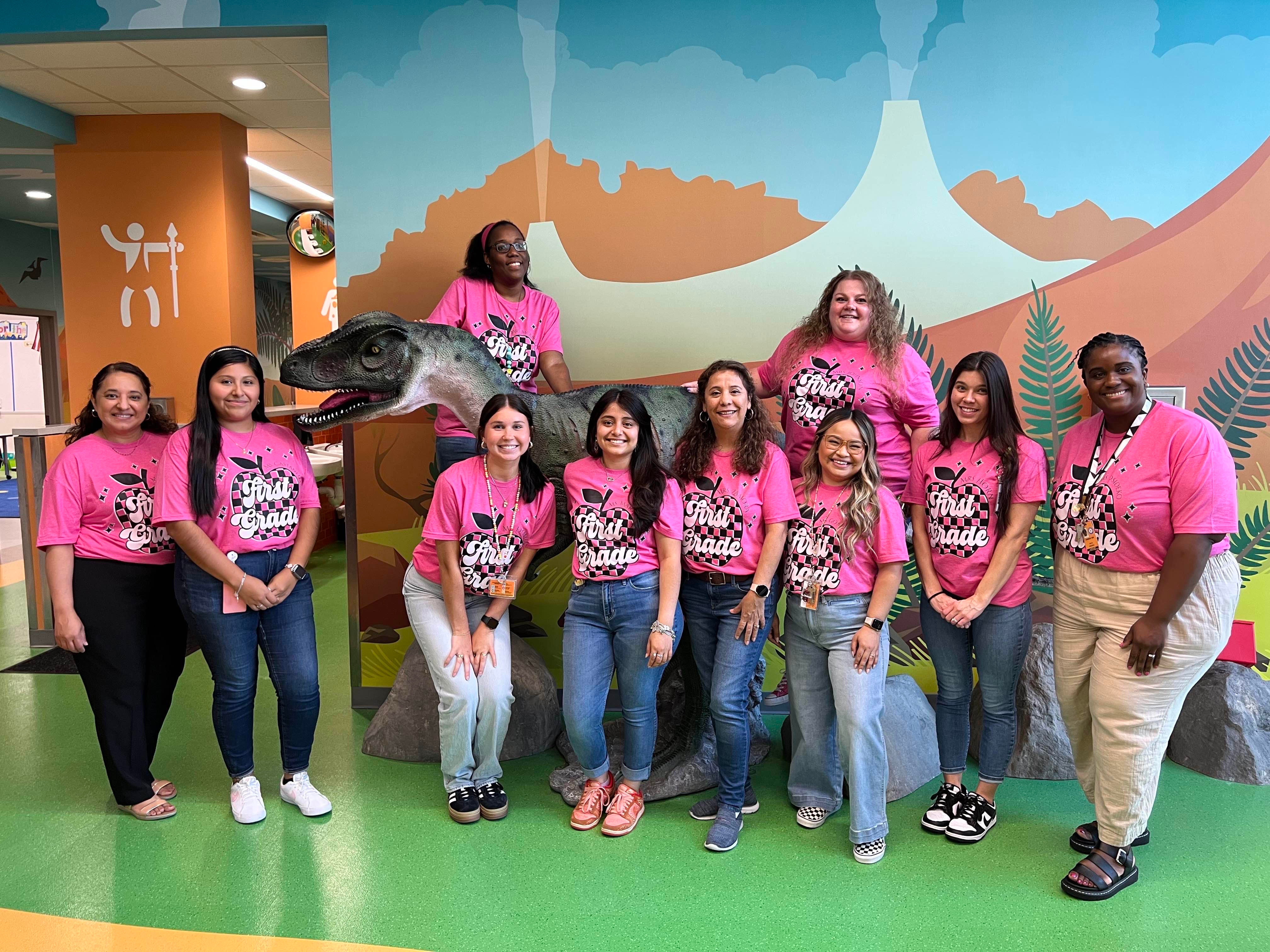 group of people posing with dinosaur statue