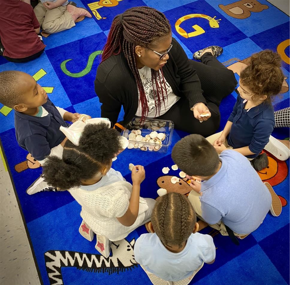 Teacher sitting on the floor playing games with her students