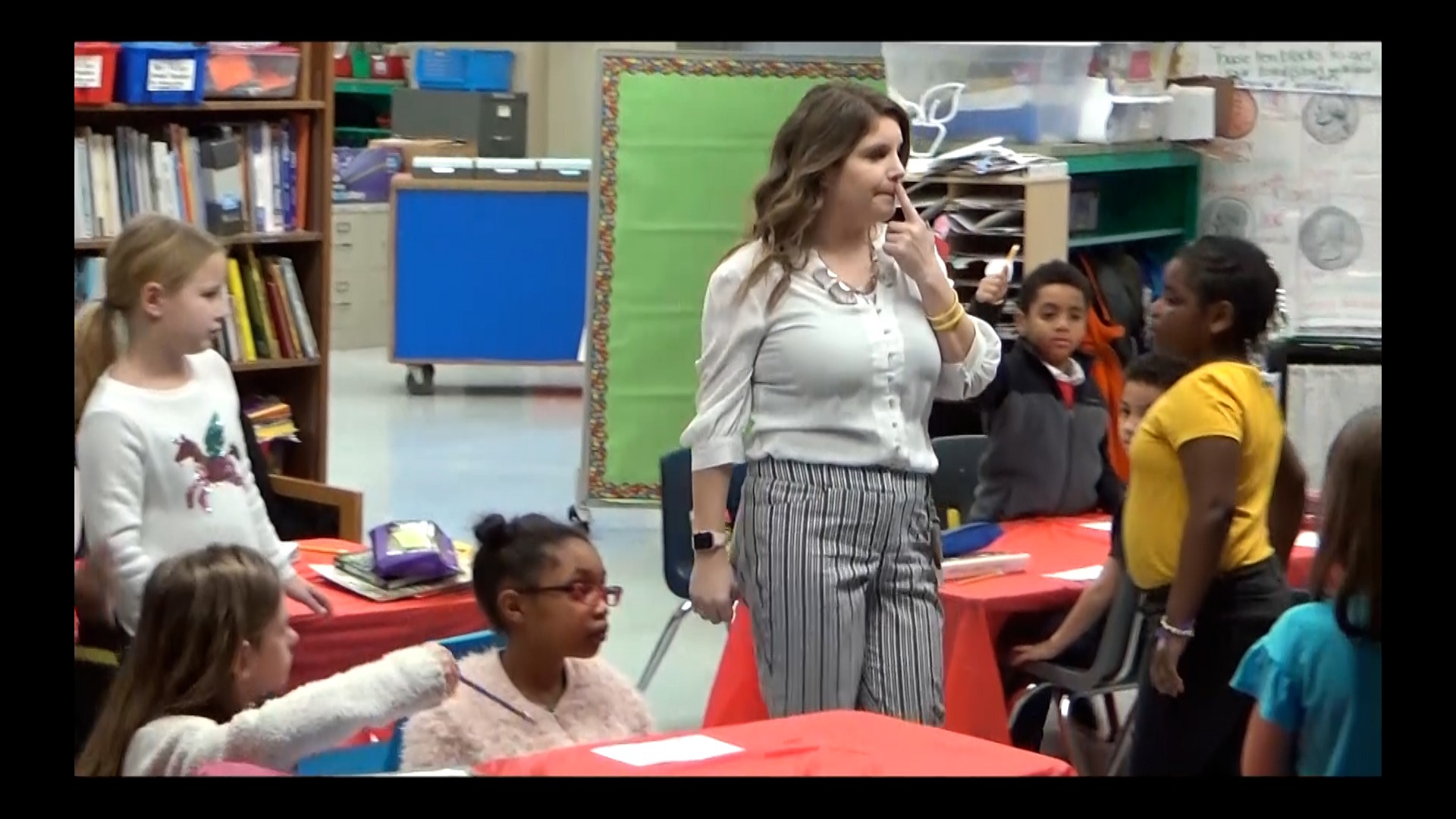 Image of female teacher in class waiting on an answer from a student