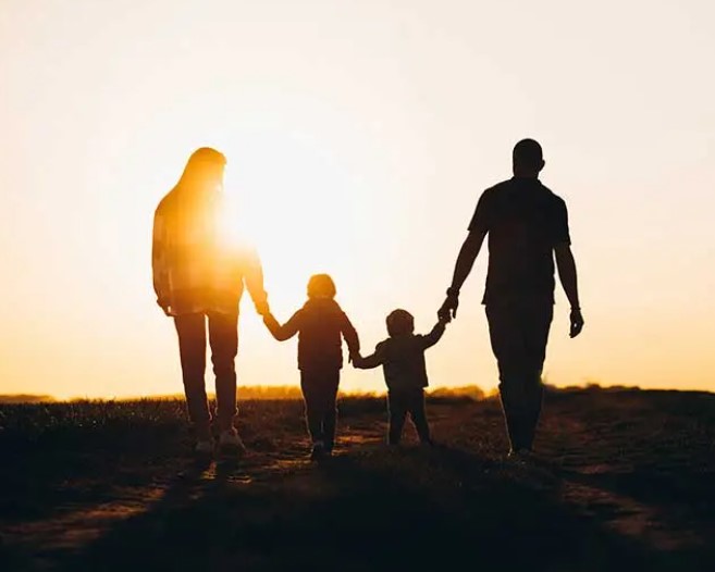 Image of two adults and two children walking in the sunset 