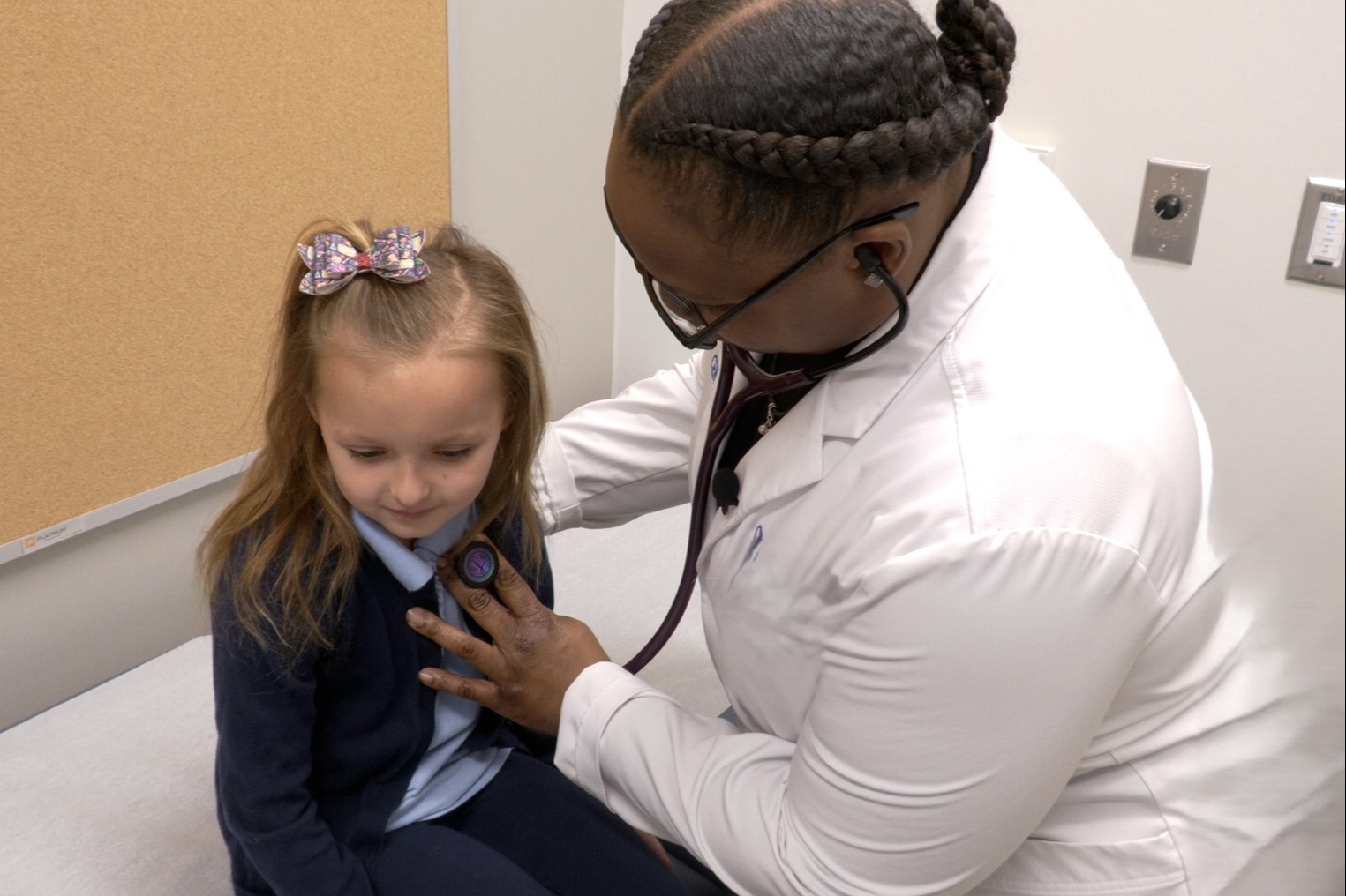 Image of a nurse listening to the heartbeat of a student with a stethoscope