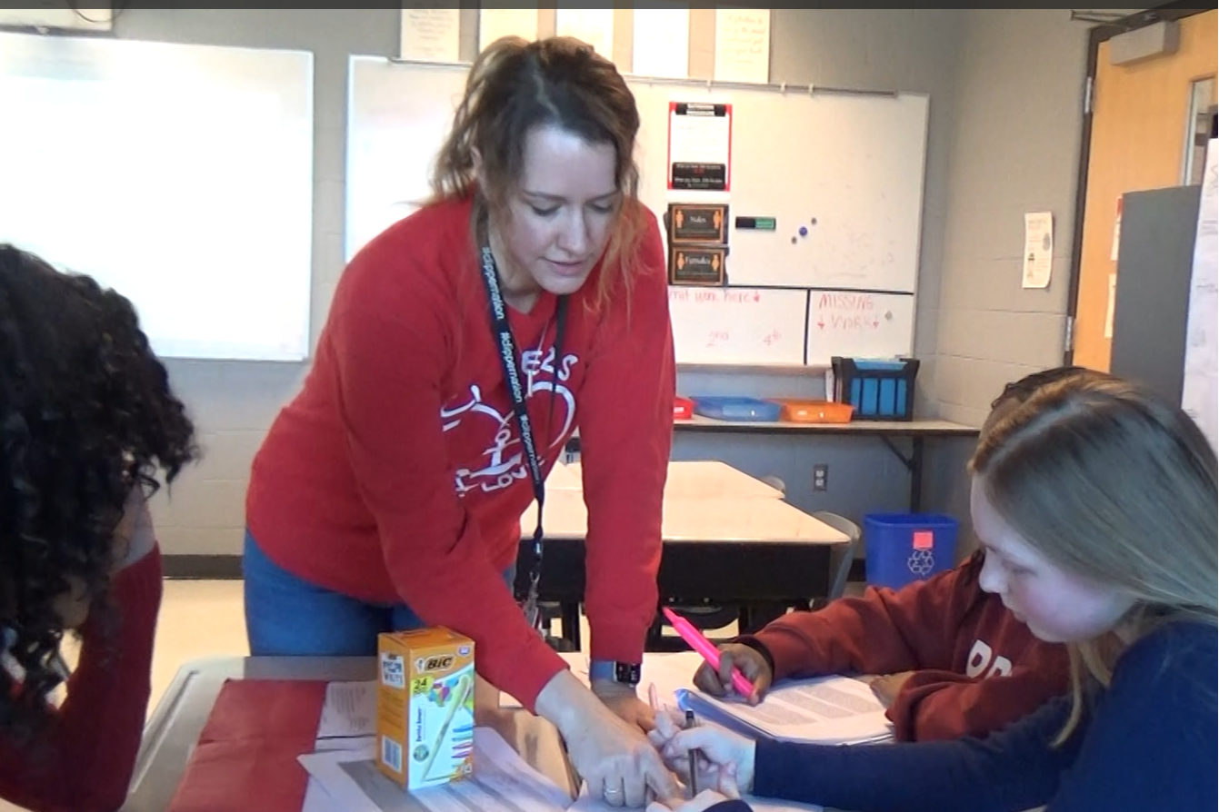 Image of a teacher in class talking with students about a project