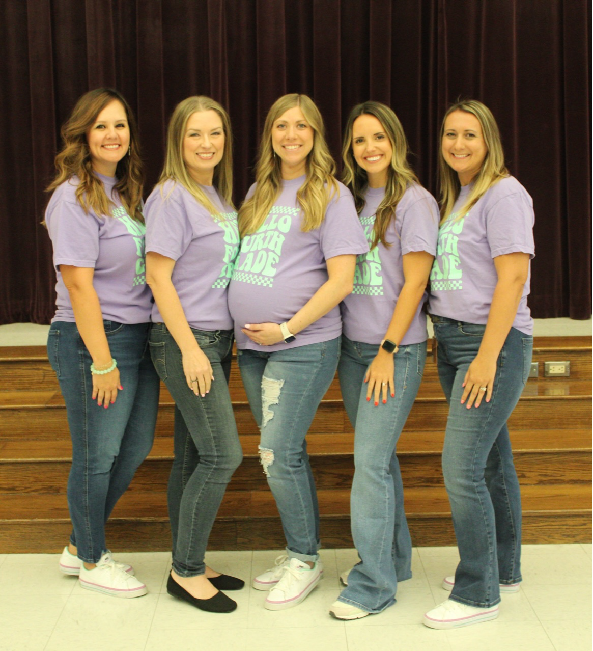 group of teachers in white shirts standing posing inside school building