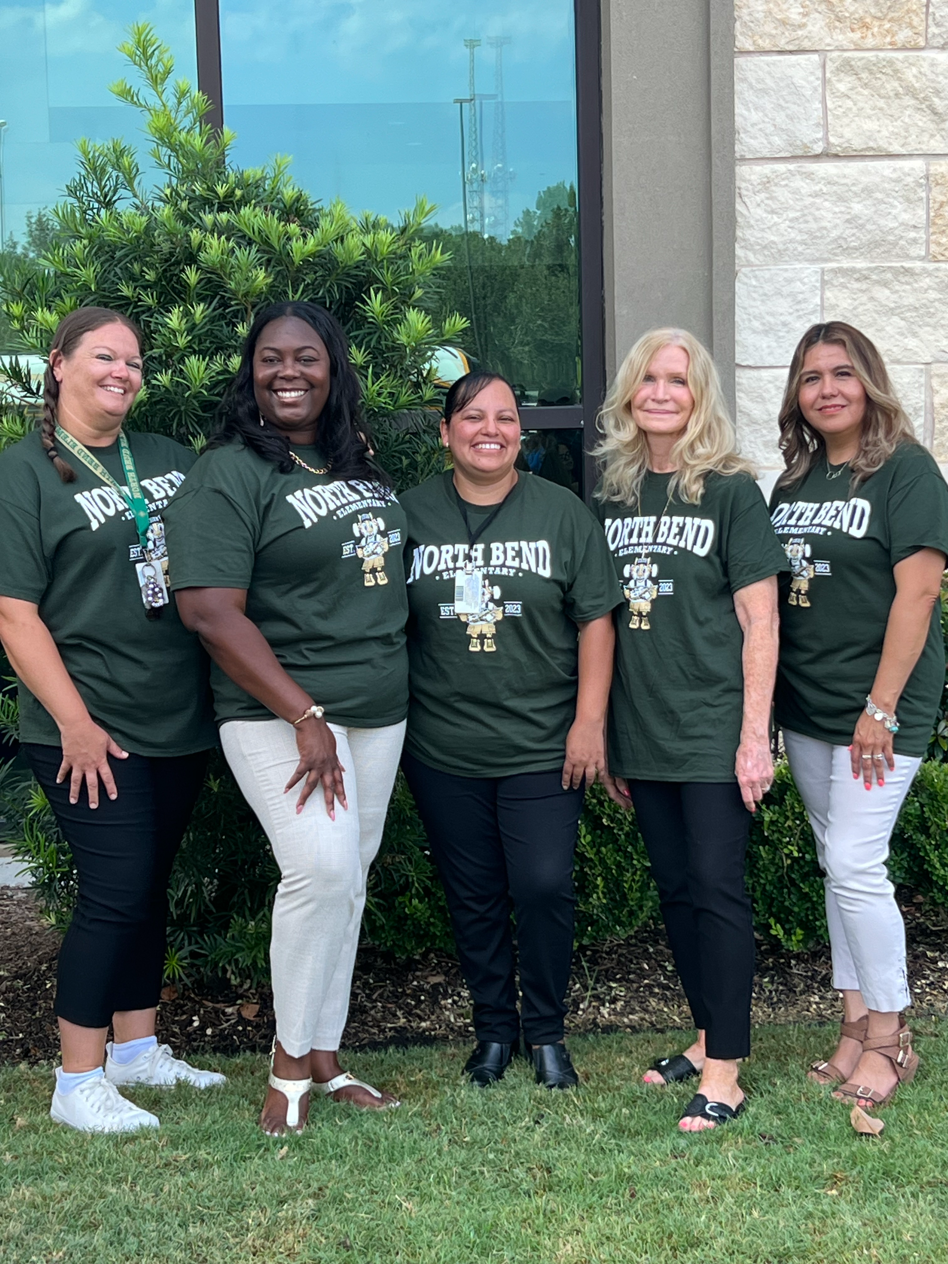 group of 5 people standing posing in green shirts outside