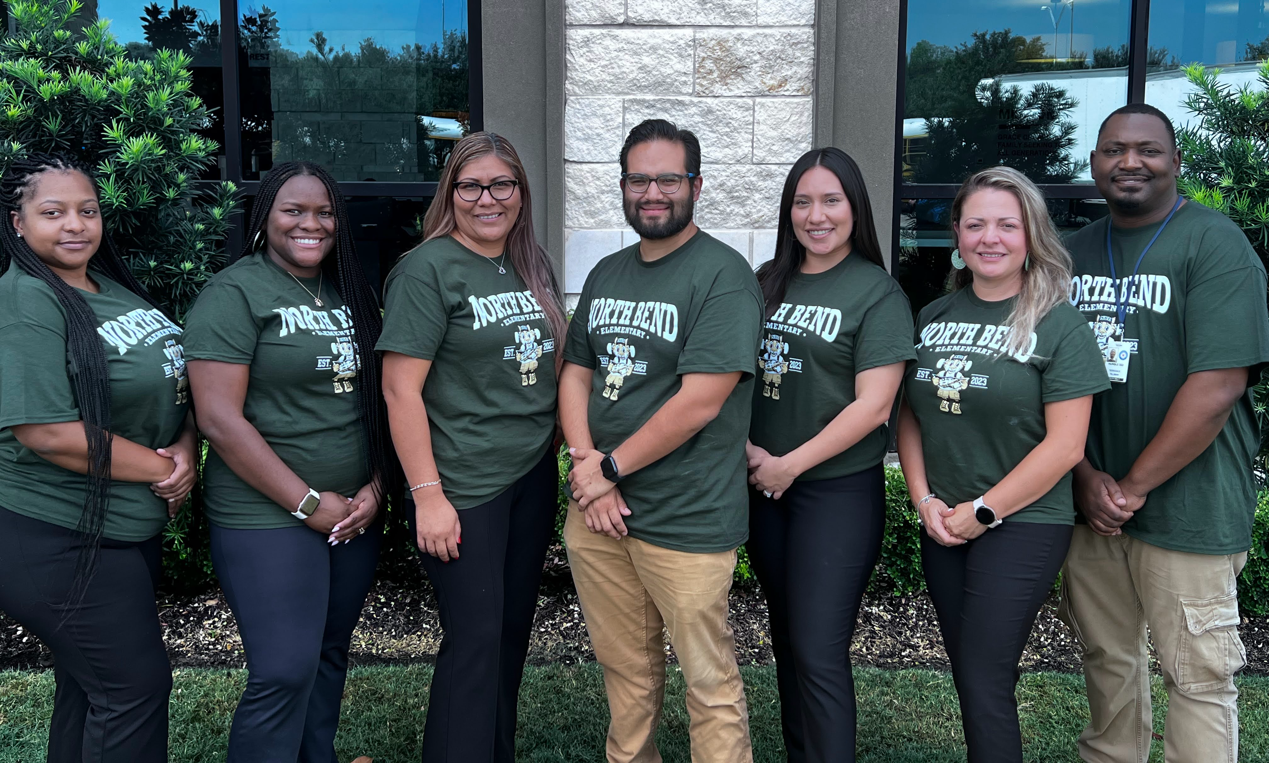 teachers in green shirts standing posing outside