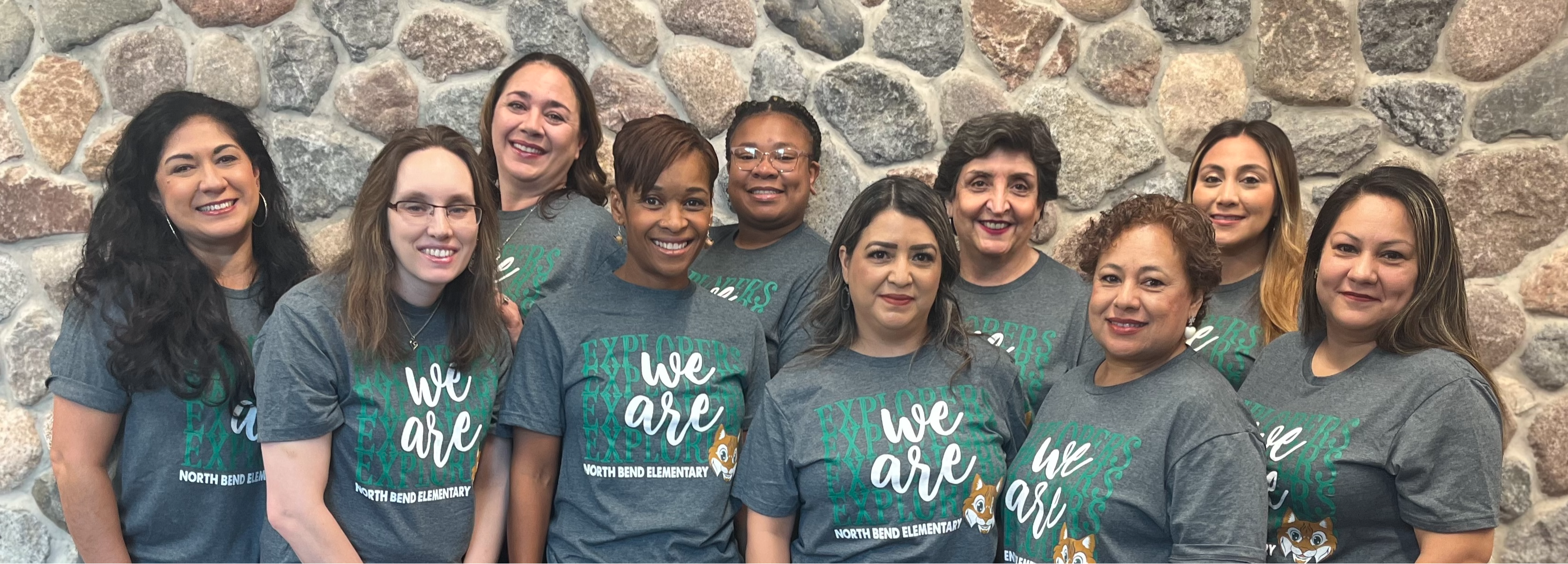 group of teachers posing in green shirts outside