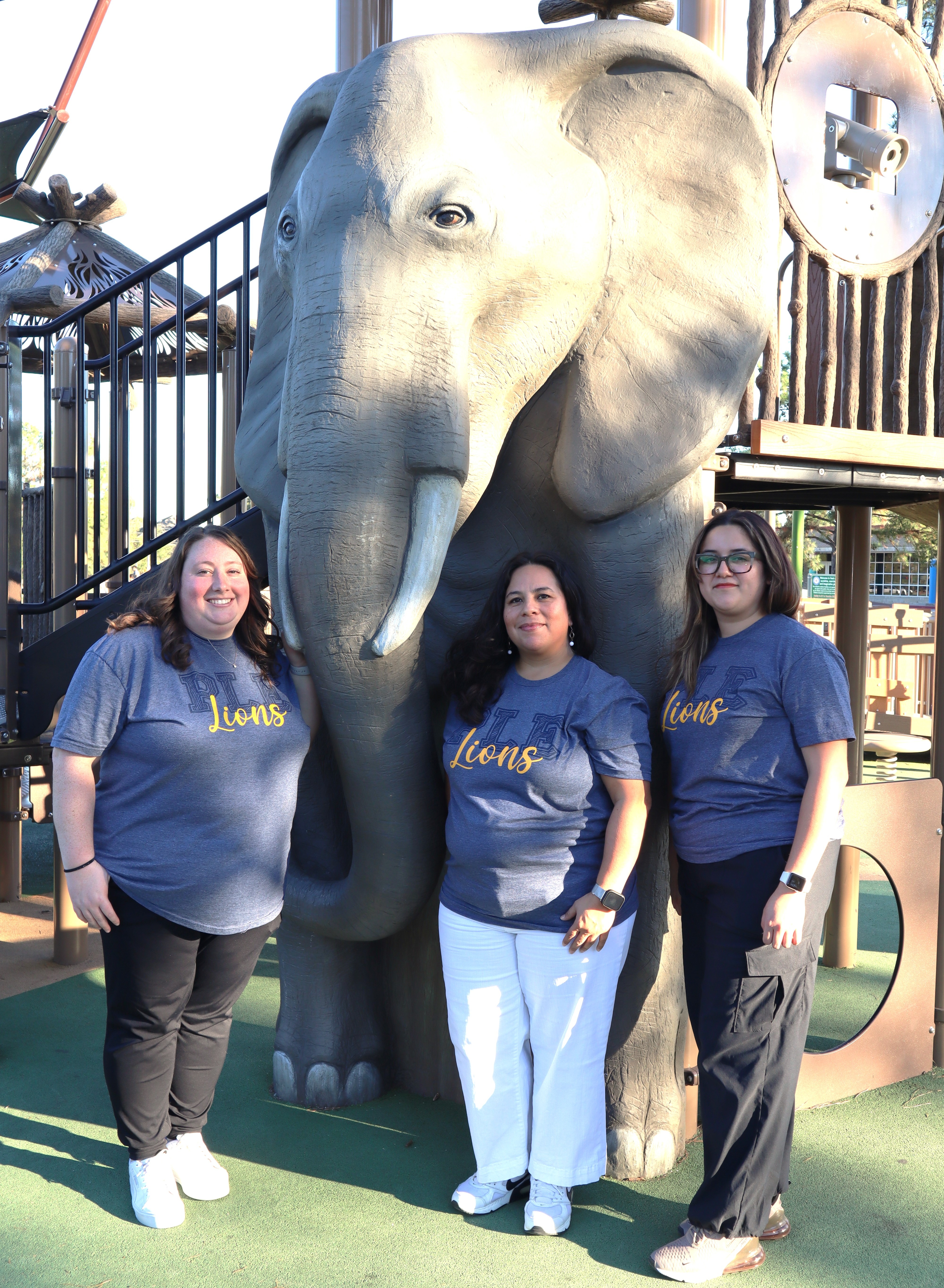 group of teachers posing by playground equipment