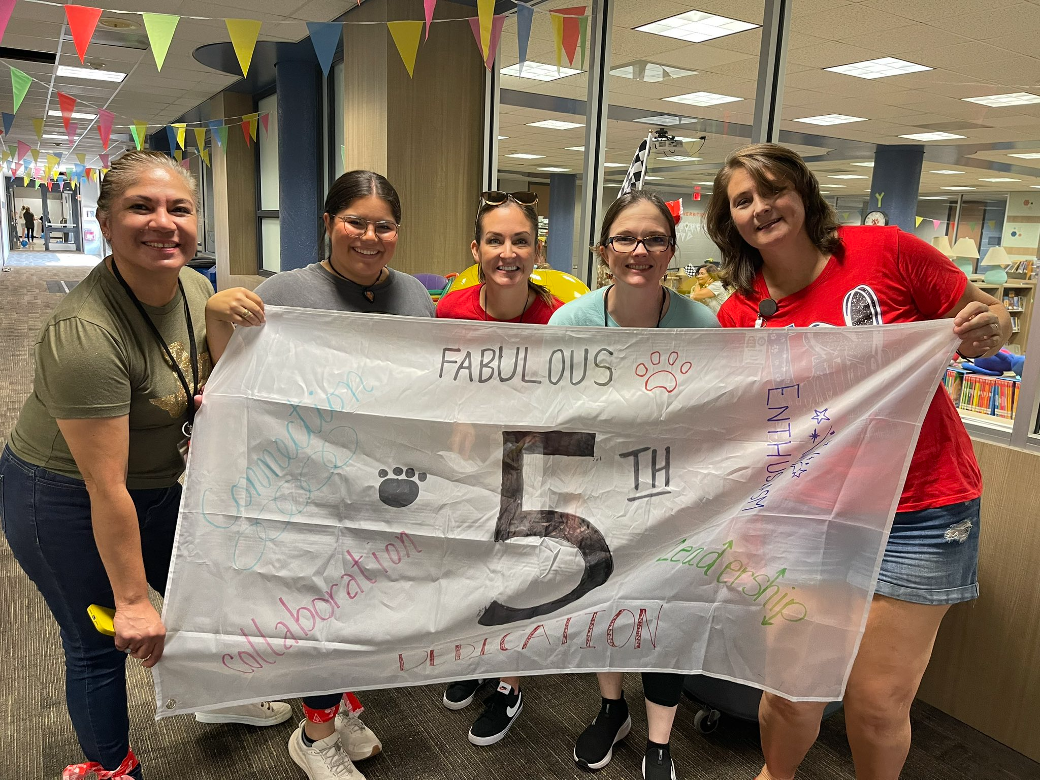 group of ladies standing in school hallway holding banner