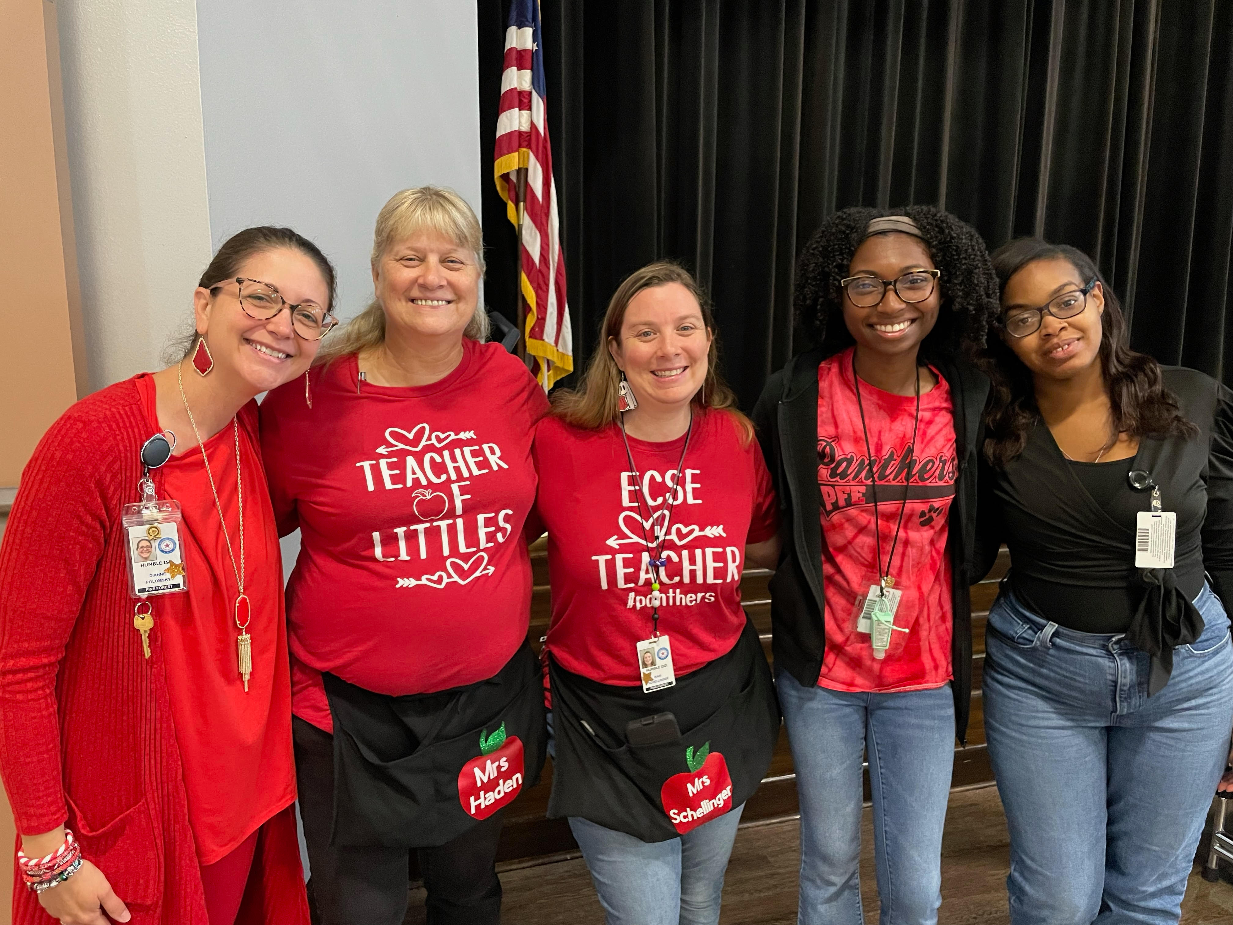 Pre-K teachers standing posing in front of black stage curtain