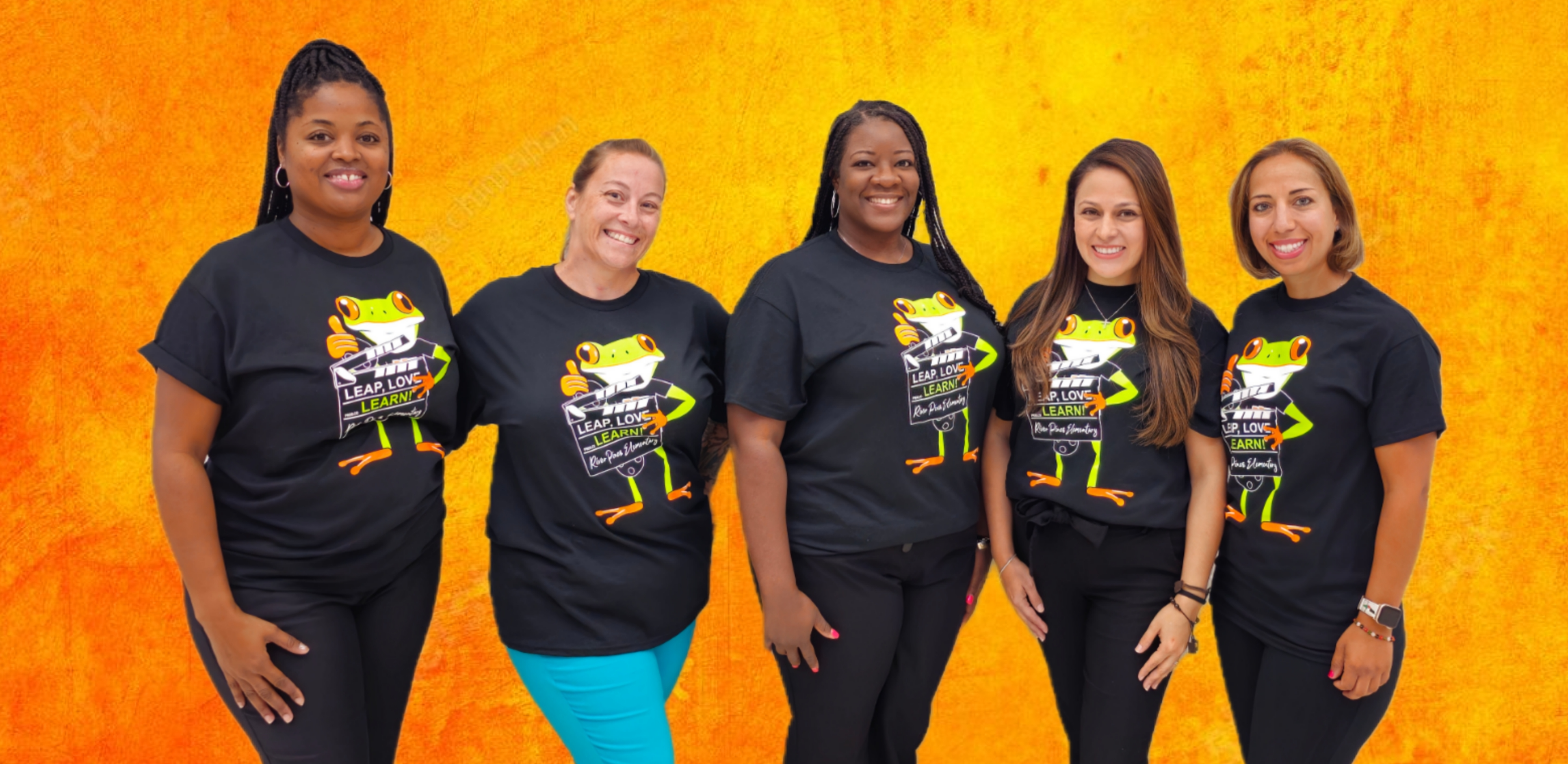 kinder team in orange shirts standing posing in front of gray brick wall