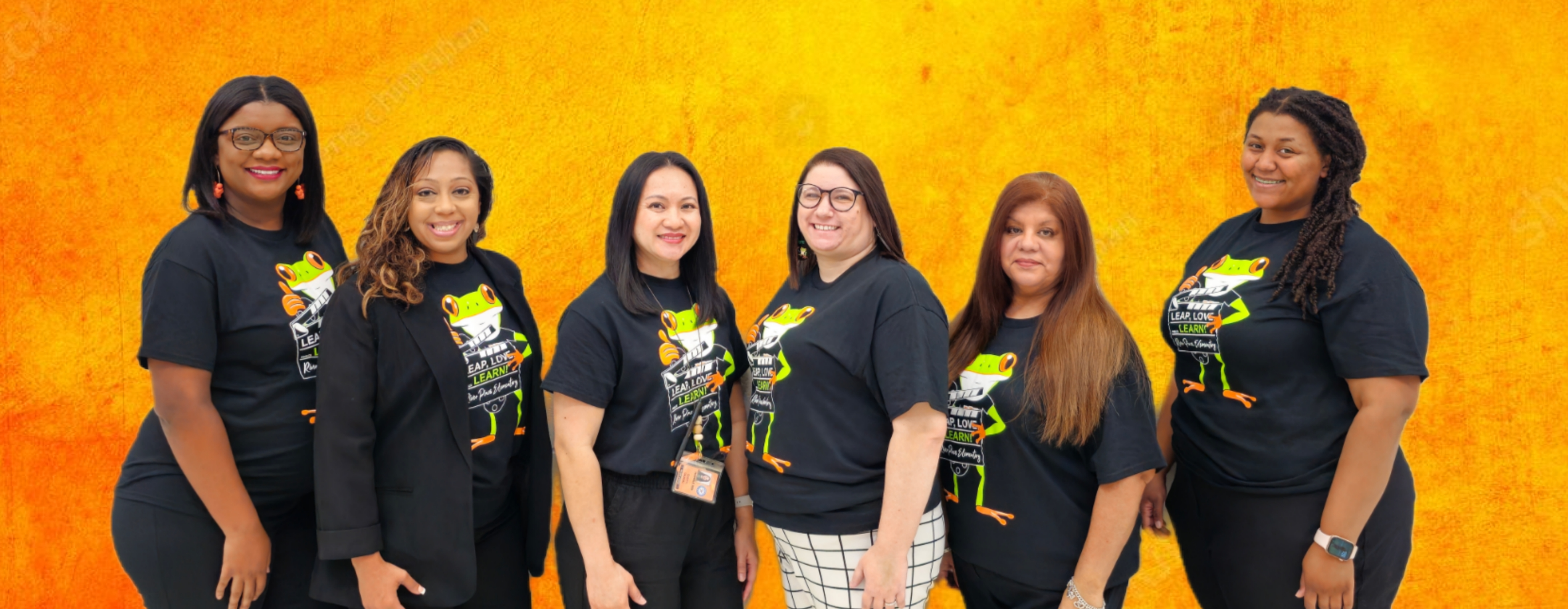 RPE 2nd Grade teachers in orange shirts standing posing in front of gray brick wall