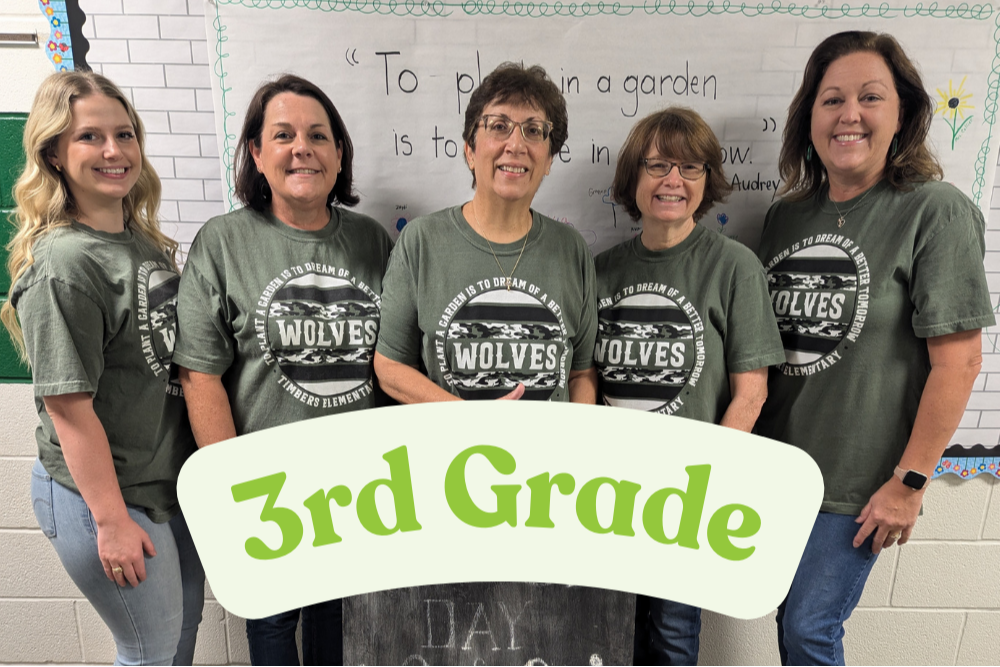 3rd Grade Team posing in front of colorful backdrop in school hallway