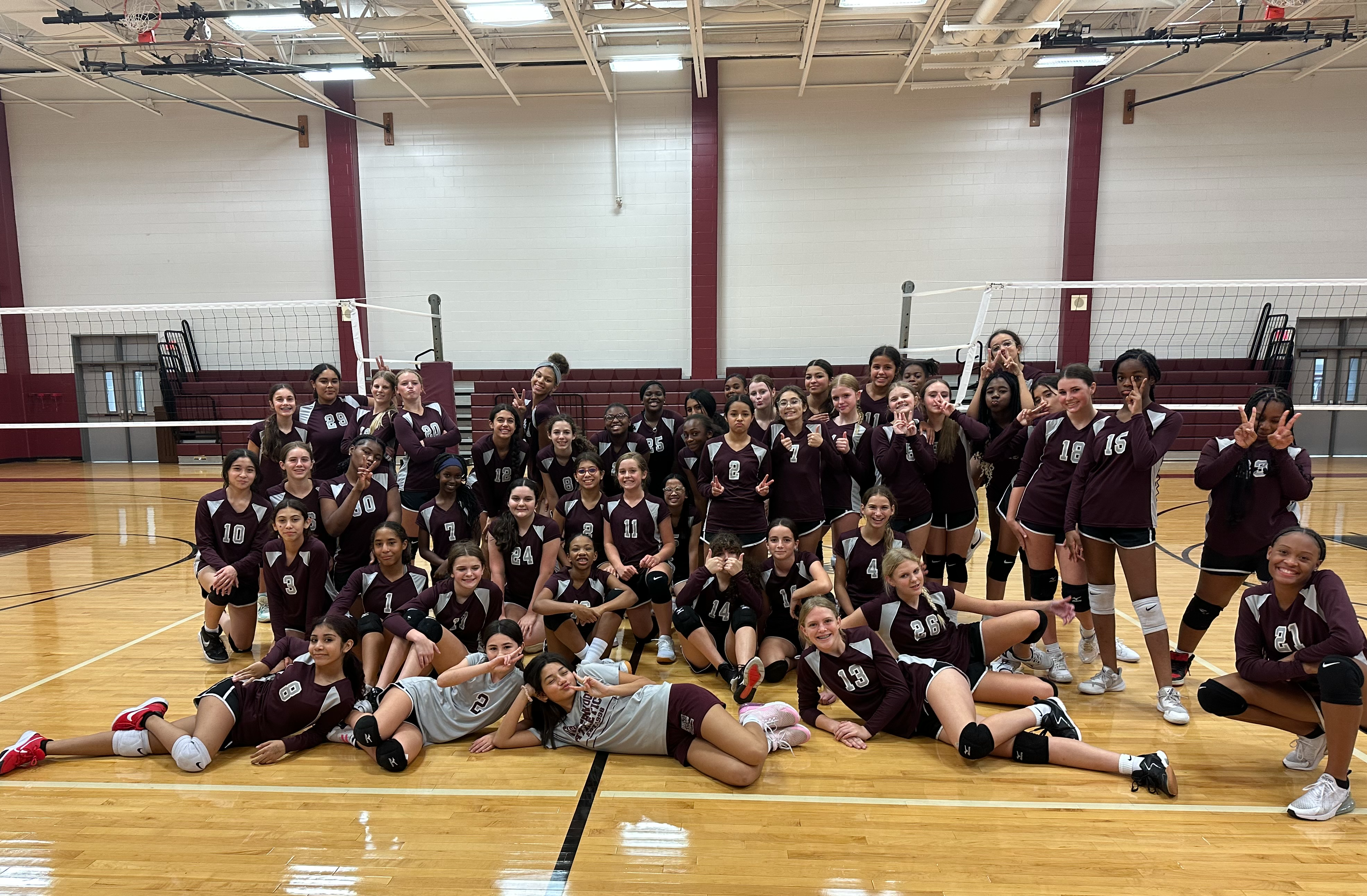 Students posing on gym floor in athletic uniforms