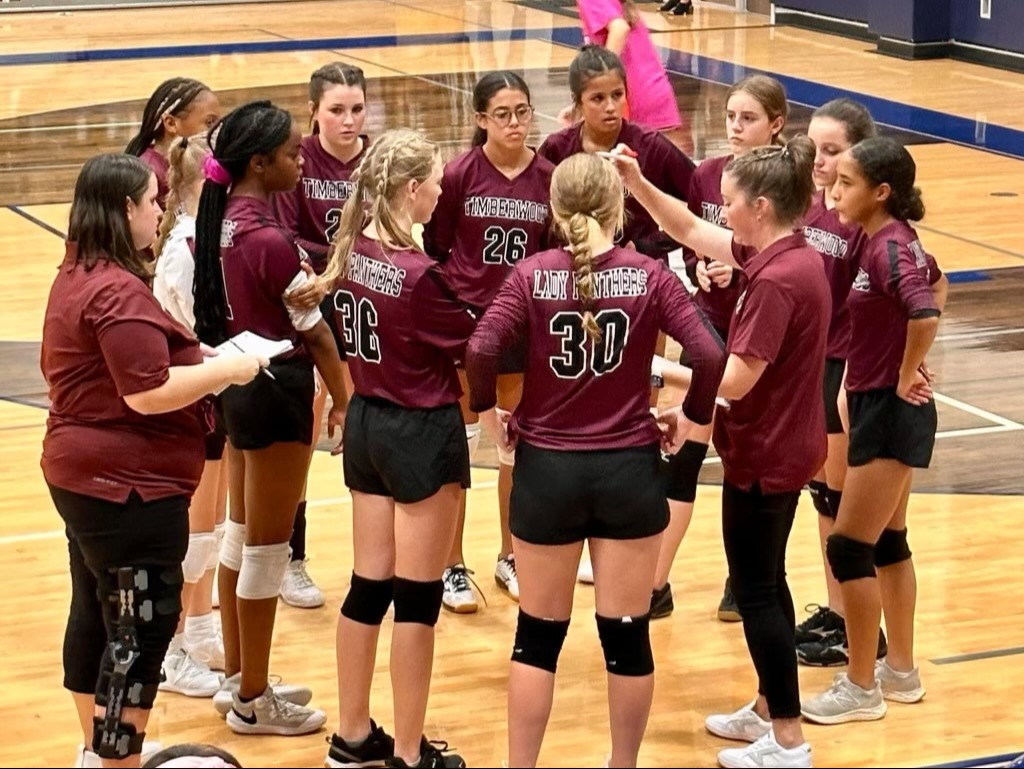 Group of students standing in circle in athletic uniform in gym