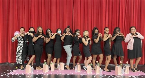 group of students in black attires standing posing in front of red curtain