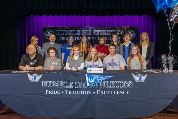 group of people posing behind signing table for Humble ISD Athletics