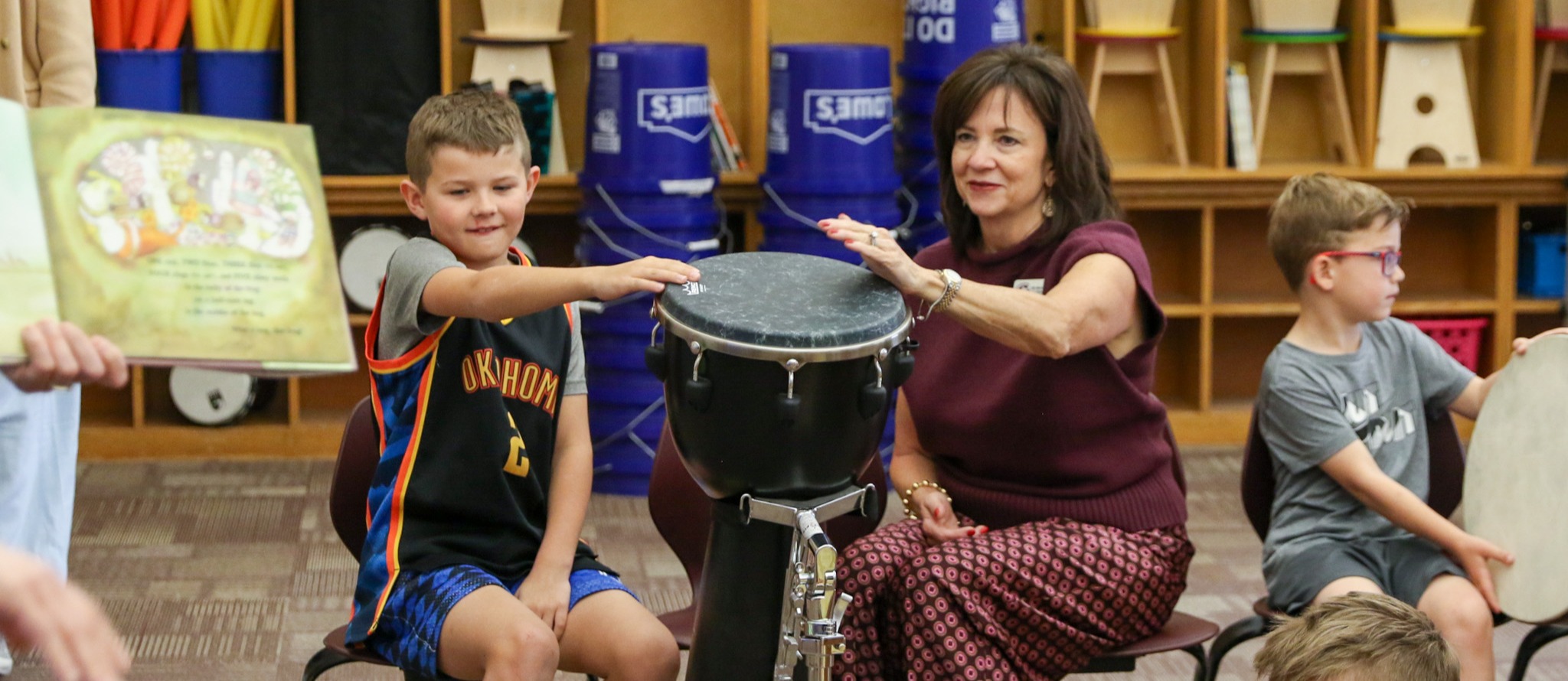 Student and Dr. Stacey Butterfield seated and playing a drum together
