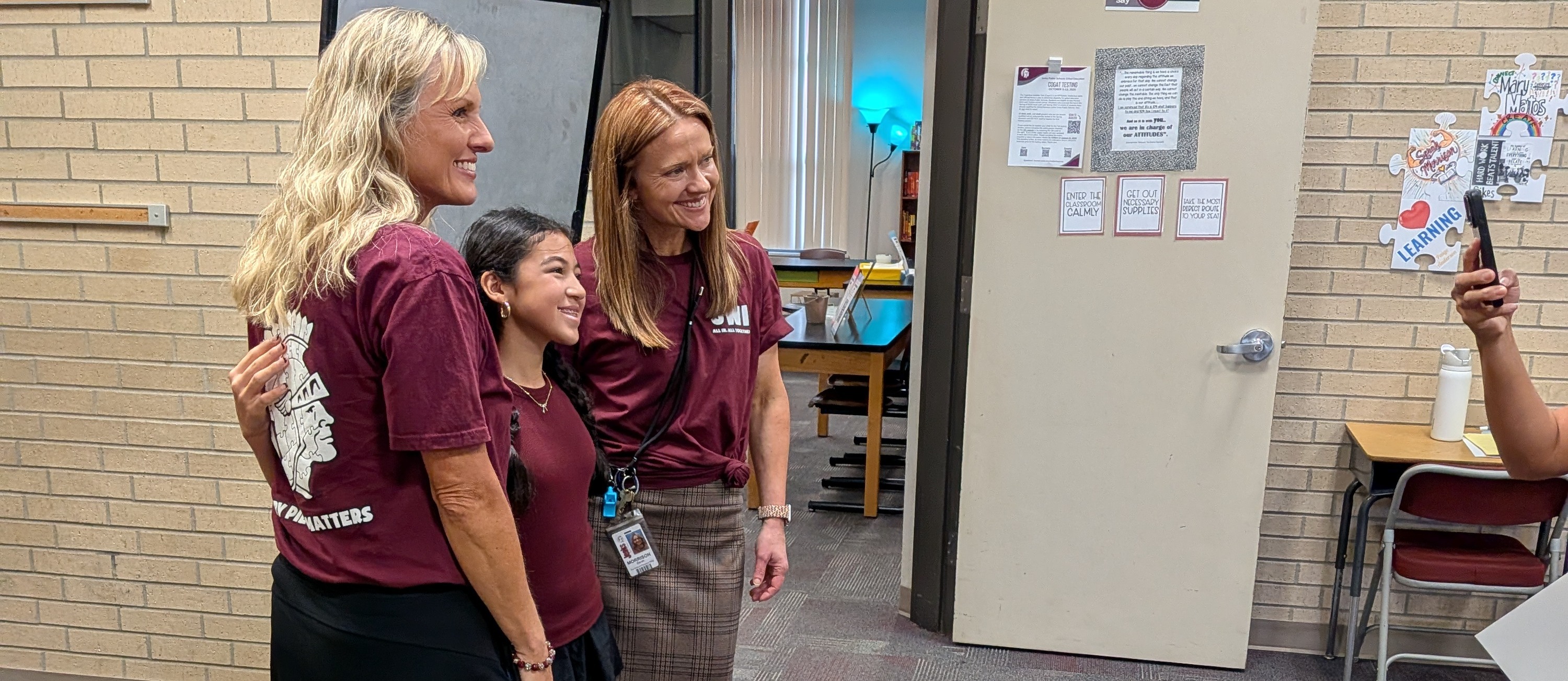 Two sixth grade teachers posing with a new sixth grade student during meet the teacher