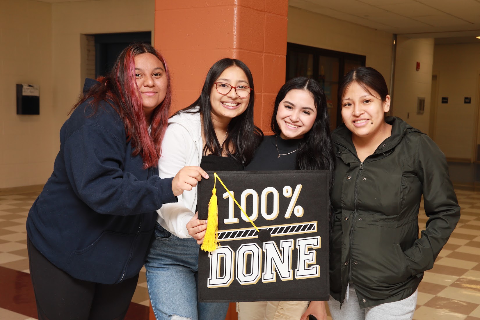 students posing with giant graduation cap smiling