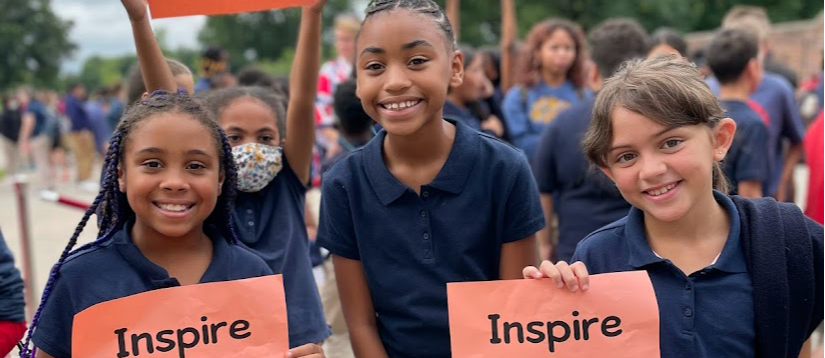 three students holding signs that say 'inspire change'