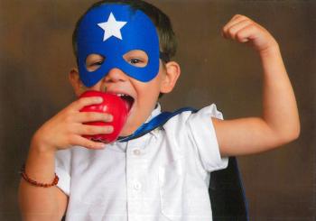 Super hero kid eating an apple