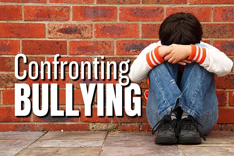 Picture of a kid with his head in his hands and lap with the words Confronting Bullying