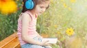 little girl listening to something with blue headphones