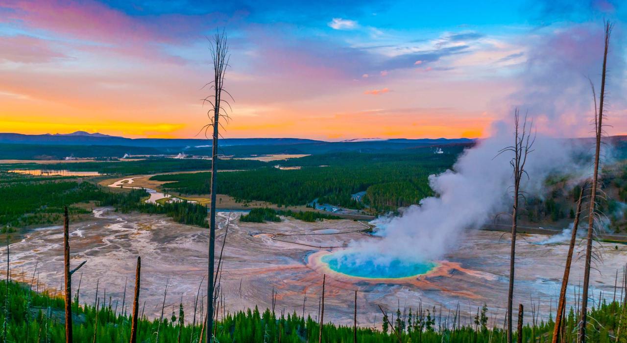 a early morning sunrise at Yellowstone National Park with lush trees, steaming hot springs and a gorgeous view that spans for miles