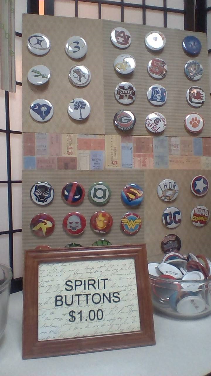 Image of custom made buttons displayed in a frame with sign that reads "buttons $1"