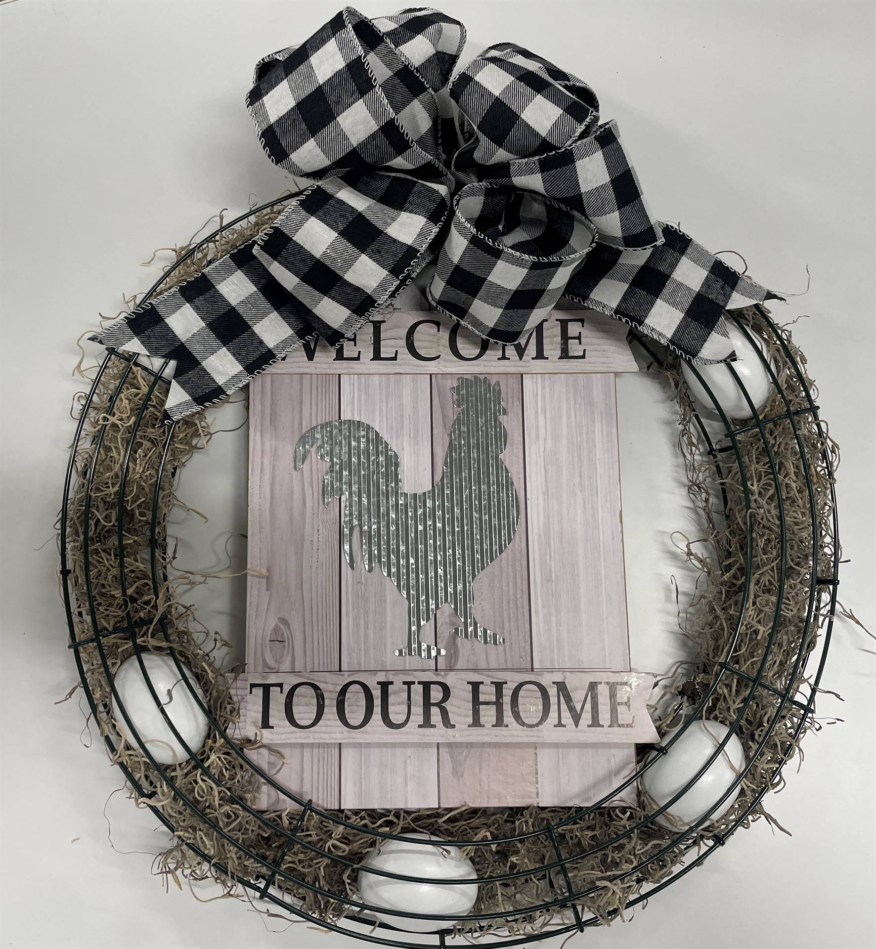Farmhouse style welcome wreath with a picture of a chicken and eggs and a black and white plaid bow