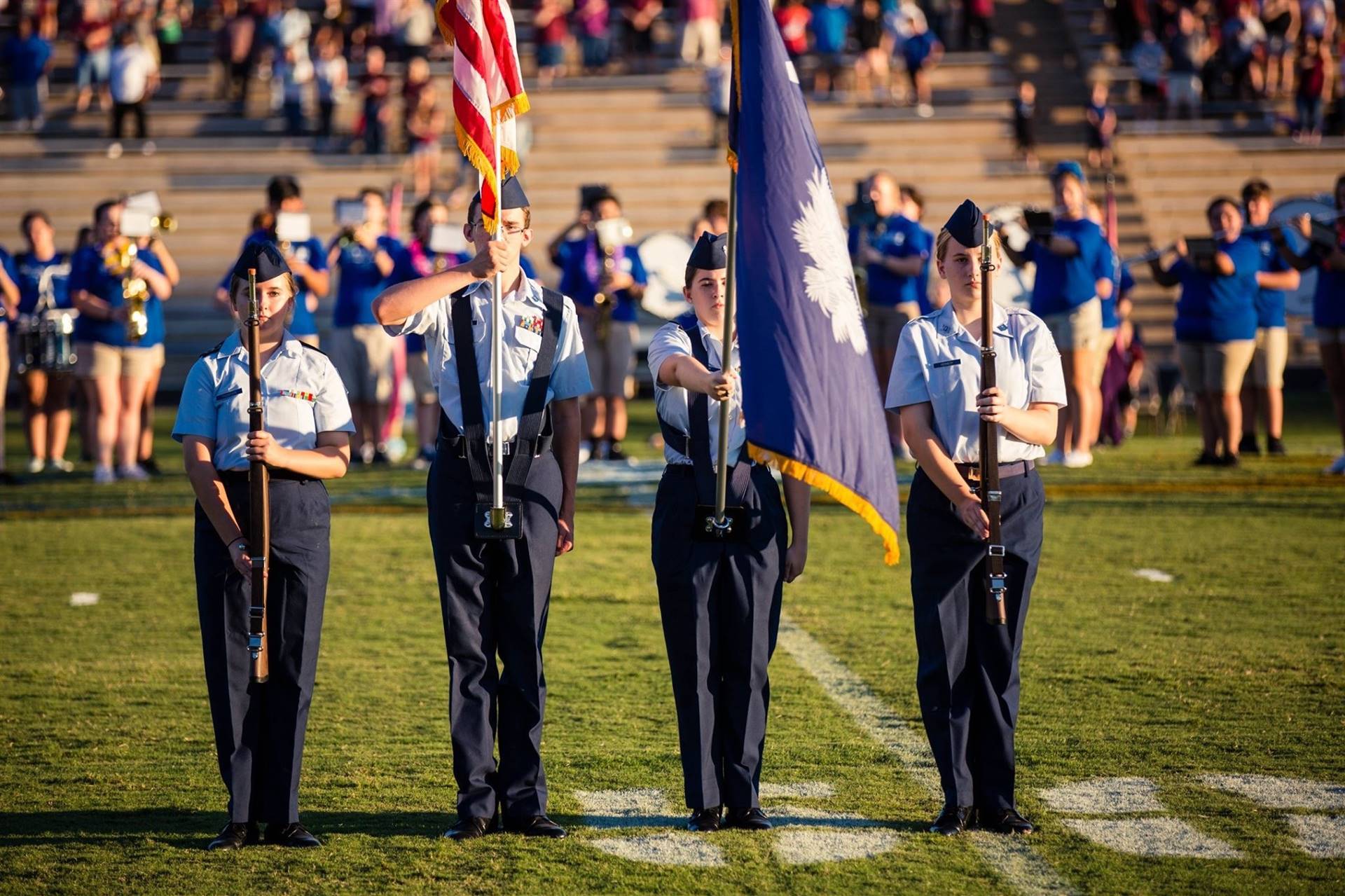 JROTC members holding flags and firearms on the football field