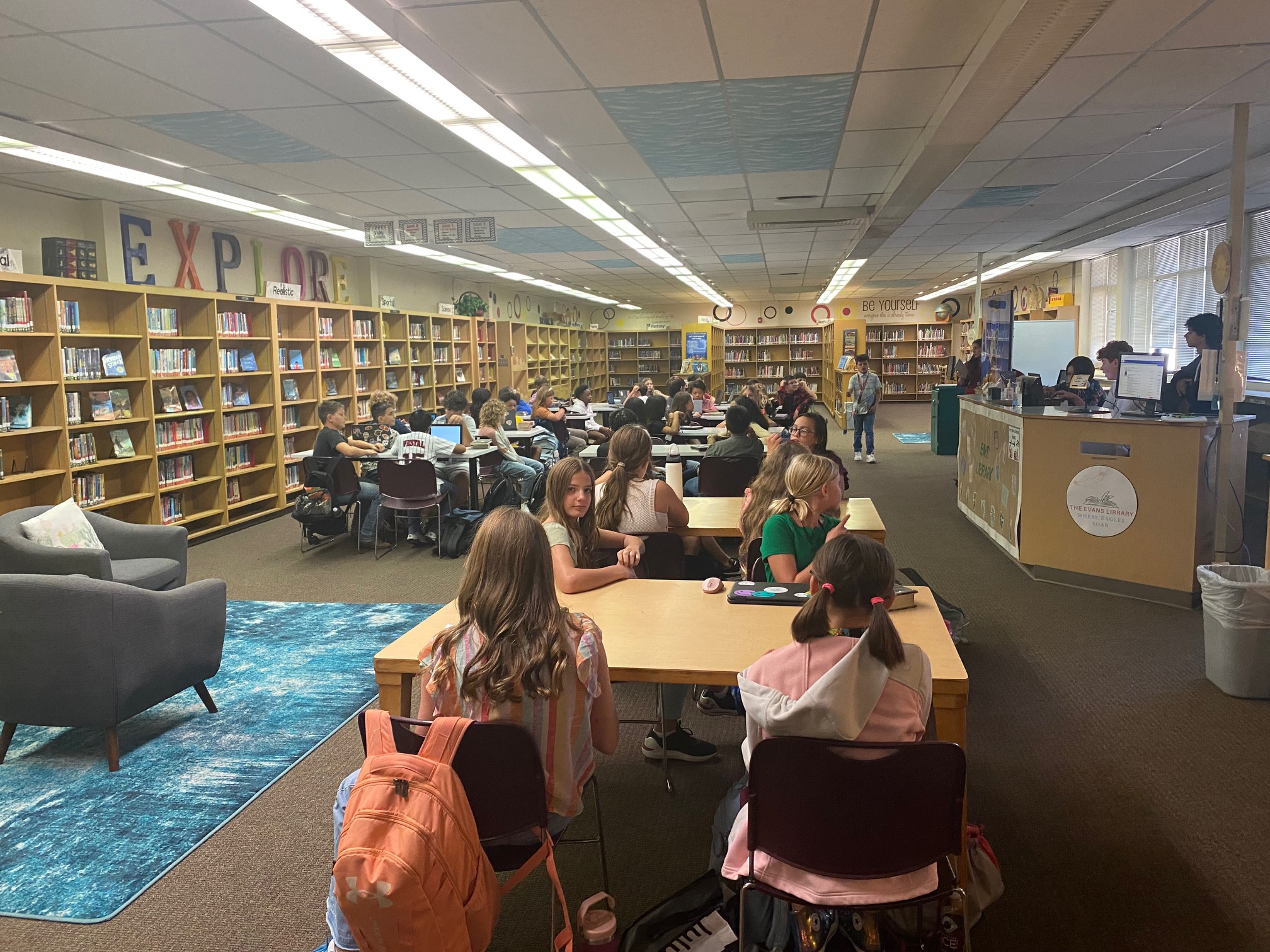 Students listening to a teacher speak in the library