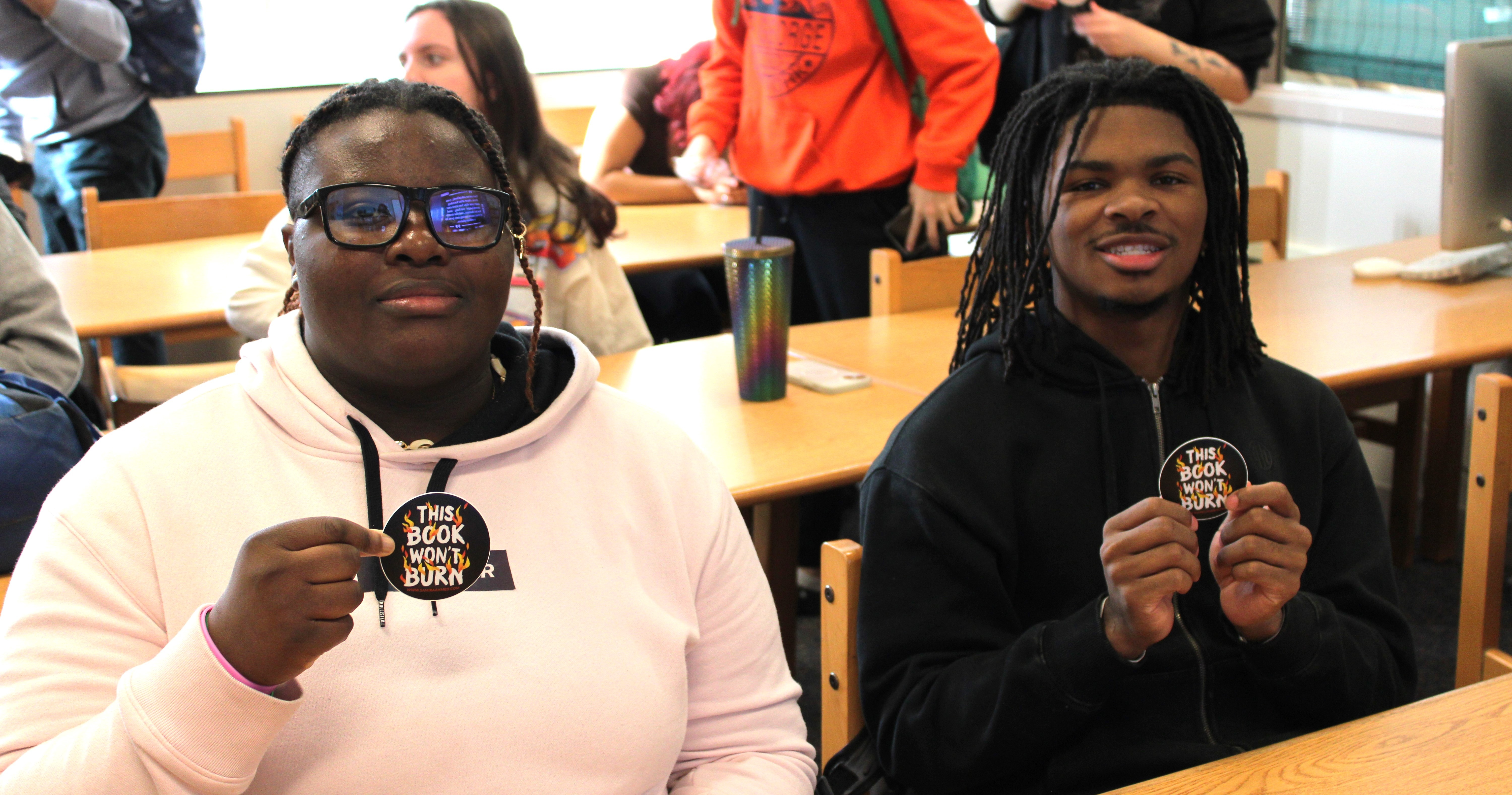 two students hold up stickers at author visit