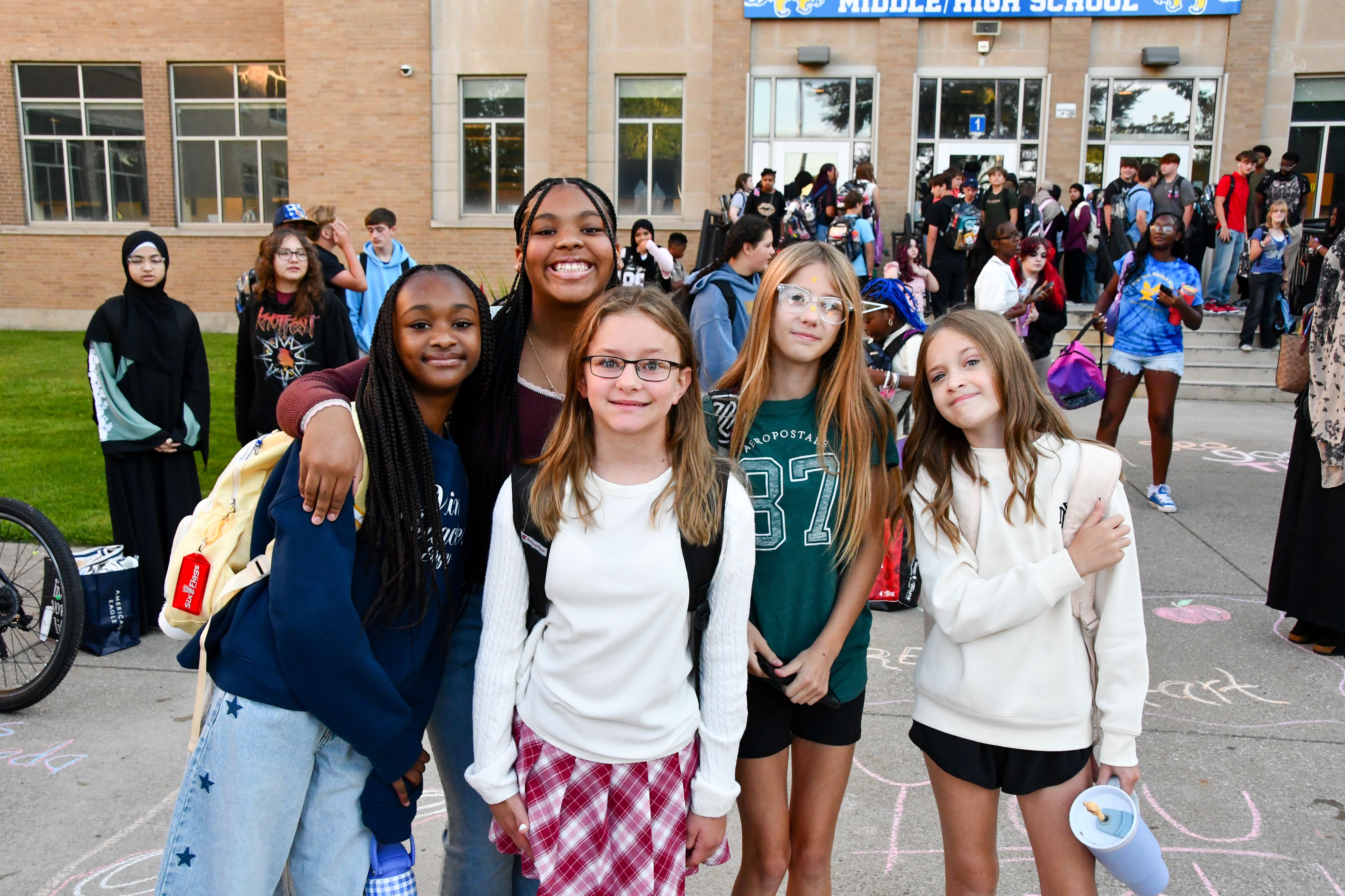 Group of 5 students standing outside of school
