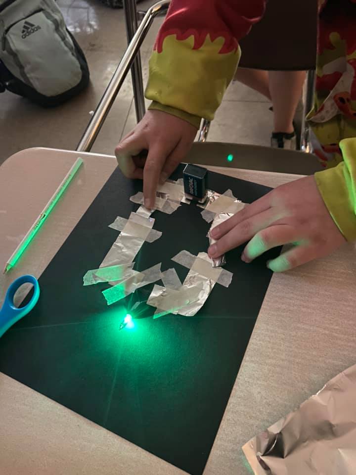 students teach each other how to turn on christmas lights using current