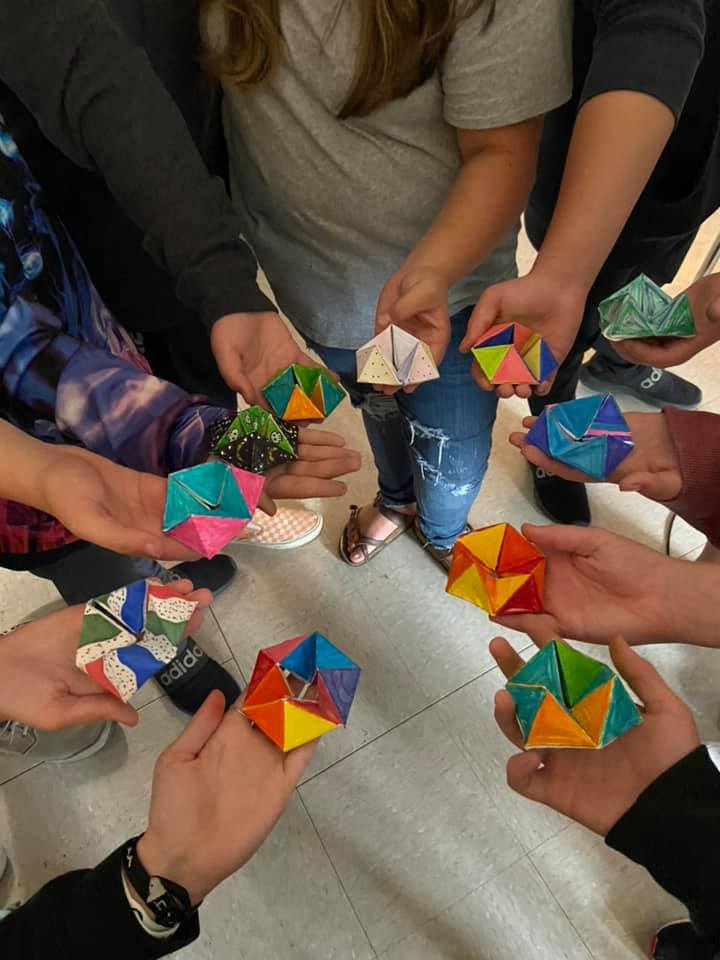 Students display homemade board game pieces made form origami folding