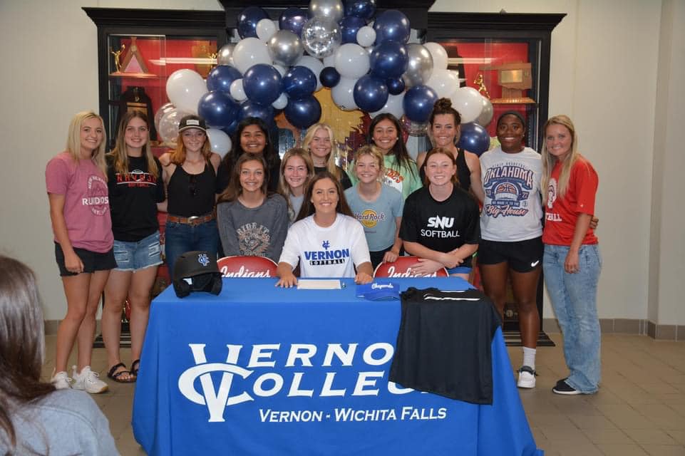 group photo of senior softball players on commitment day in college colors