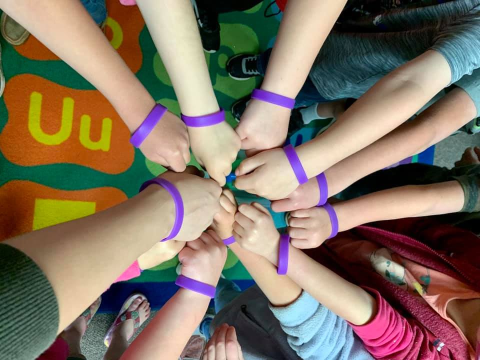 hands in circle with purple wristbands