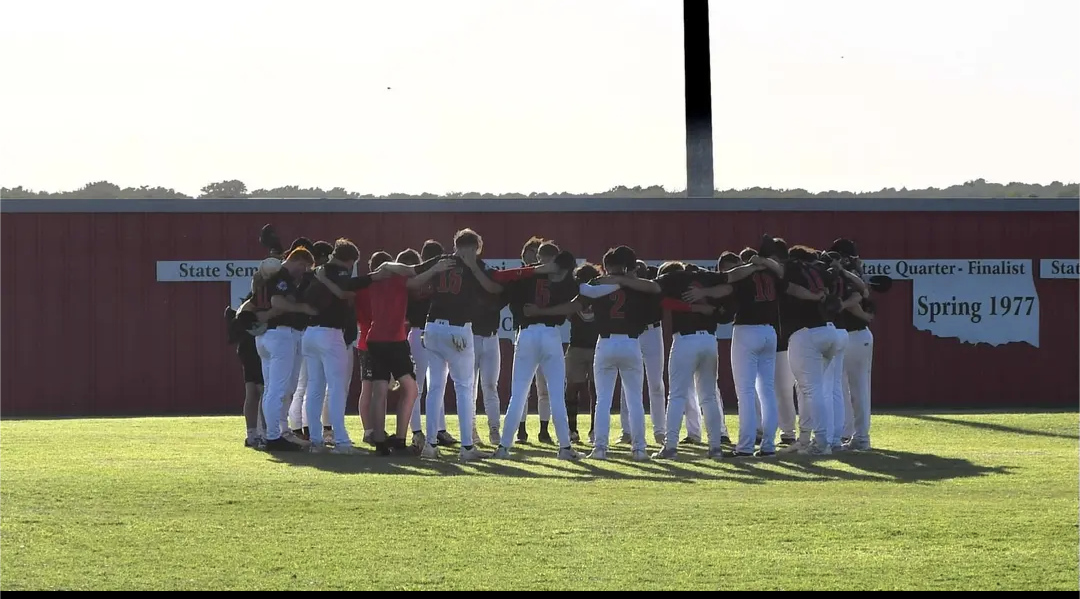 Navajo baseball team in a huddle in the outfield of the home field.