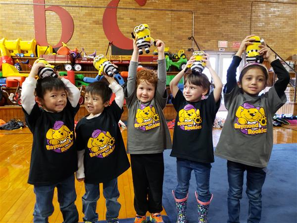 students standing and holding up a stuffed toy