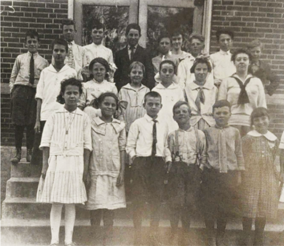 black and white photo of children smiling on school steps