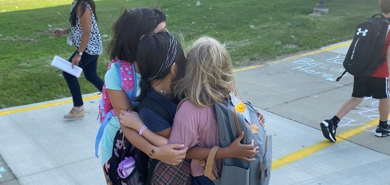 three girls group hug on first day of school