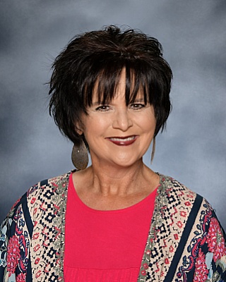 Jennifer Bowers - cropped dark hair with bright blouse and multicolor cardigan
