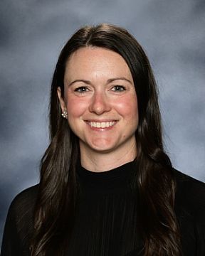 Smiling female principal with dark hair and black shirt.