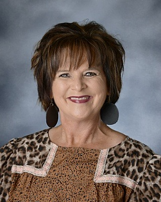 Female with cropped dark hair and leopard printed top.