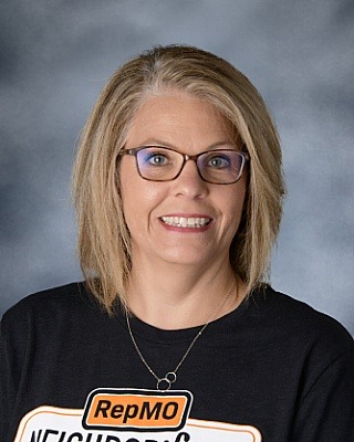 Female with cropped light hair with glasses and dark shirt.